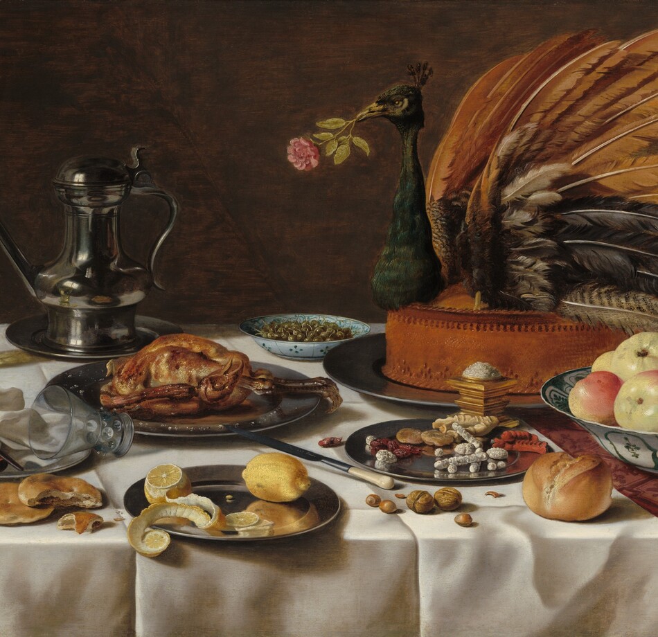 On a tabletop spread with an ivory-white cloth, plates, and white porcelain bowls containing sweets, fruit, olives, and a cooked fowl are arranged around the largest platter, which holds the head, wings, and tail of a peacock stuck into a tall, baked pie, in this horizontal still life painting. The front, left corner of the table is near the lower left corner of the painting, so the tabletop extends off the right side of the composition. The white tablecloth lies over a second cloth underneath, which is only visible along the right edge. The cloth underneath has a leafy, geometric pattern in burgundy red against a lighter, rose-red background. The peacock pie is set near the back of the table, to our right, so it fills the upper right quadrant of the composition. The bird holds a pink rose in its beak. In front of it, near the lower right corner of the painting, a white porcelain bowl painted with teal-green floral and geometric designs holds about ten pieces of pale yellow and blush-red fruit. A pewter plate next to it, to our left, holds dried fruit and baked, stick-like sweets, some covered with white sugar. A pile of salt sits atop a gold, square vessel between the sweets and the peacock pie. Another blue-patterned, white porcelain bowl filled with green olives sits near the back of the table next to a lidded, pewter pitcher with a long spout. Other pewter plates hold a baked fowl, like a small chicken, and, closest to us, a partially cut lemon with its peel curling off the plate. Nuts, more fruit, an ivory-handled knife, bread rolls, and flat biscuits sit on the white cloth among the plates. One glass with a wide stem covered in nubs and a flaring bowl sits near the back, left corner of the table, filled with a pale yellow liquid. An empty glass lies with the upper rim on another pewter plate, to our left. Also on the plate is a bunched up white napkin and a leather case for the knife. The background behind the still life is brown.