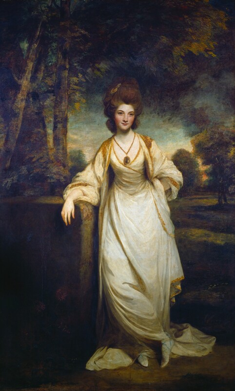 A pale-skinned woman wearing a cream-white dress stands in front of a shadowy landscape in this vertical portrait painting. Facing us, the woman looks directly out with dark gray eyes under gently curving brows. She has a somewhat wide nose, slightly smiling, bow-shaped lips, flushed cheeks, and a pointed chin. Her brown hair is pulled back and up into a loose, tall style. A palm-sized medallion hanging from a gold chain falls low on her chest. The low neckline of the dress, which is pulled around the torso like a wrap dress, is lined in gold. The train of the long skirt is pinned between her crossed ankles and pools behind her feet. She wears white, sandal-inspired shoes wrapped with blue lines. A coat with voluminous sleeves in the same deep white color as the dress falls heavily from her shoulders. She leans her right elbow, to our left, against a squared stone or ledge, and her other hand is planted on her hip. A grassy lawn stretches back to trees framing a muted blue sky in the background behind her. Sunlight glows on the horizon in the distance behind her shoulders, but the rest of the landscape falls into deep shadow.