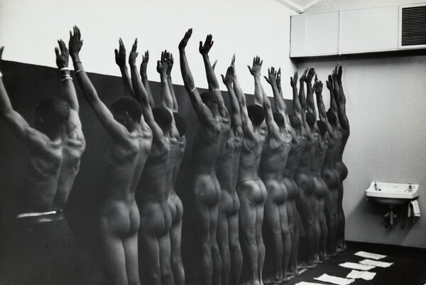 During group medical examination, the nude men are herded through a string of doctor’s offices