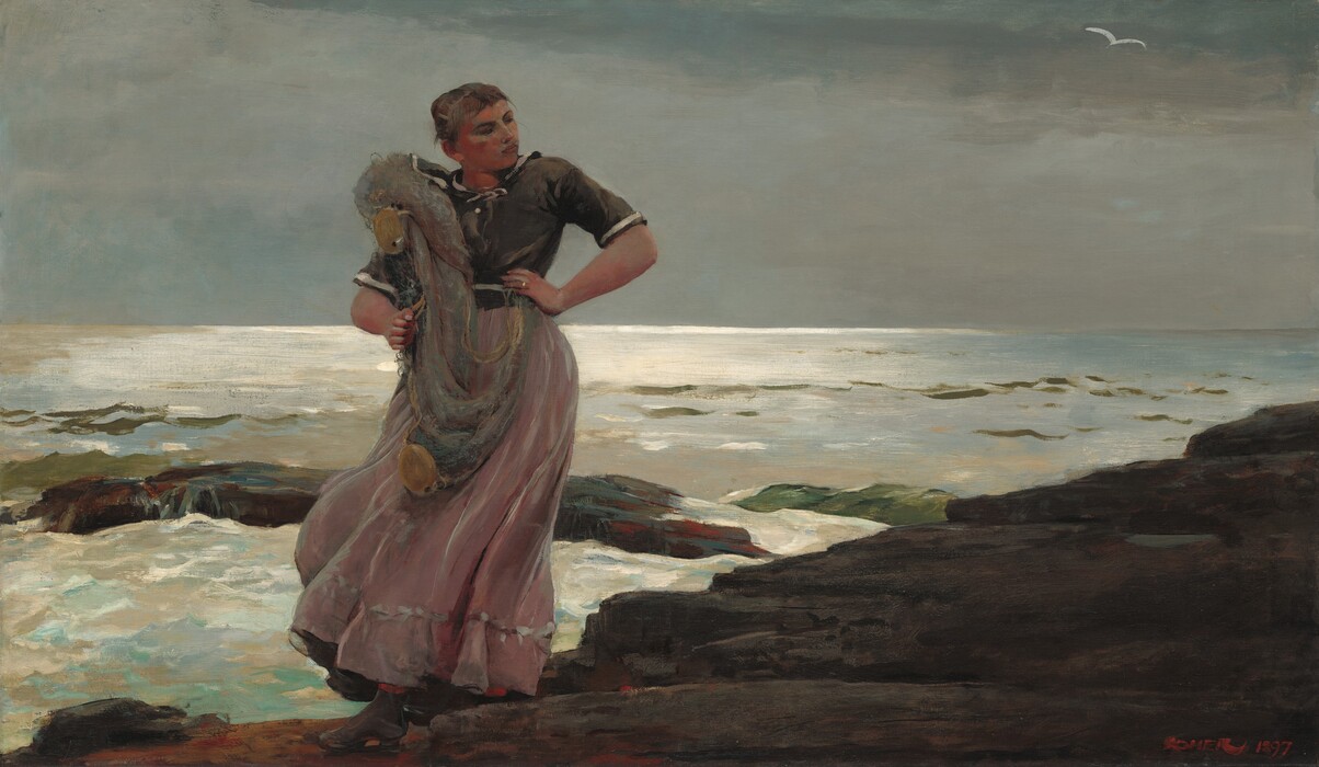A young woman with flushed, peachy skin stands on a rocky shoreline with a fishing net slung over one shoulder in this horizontal painting. Her body faces us, and she looks off and down to our right. Her left hand, to our right, is planted on her hip, and she clutches the gray net with her other hand. Her head tips toward us as her chin tucks back toward her shoulder. She has a round jaw, a straight nose, and her pink lips are set in a line. Her brown hair is pulled back and up, and bangs sweep across her forehead. Her ash-brown shirt has white bands echoing the neckline, across the waist, and around the hems of the elbow-length sleeves. Her skirt is painted with strokes of mauve pink and silvery gray. A stiff breeze sweeps the skirt to our left and reveals a glimpse of red stockings over sturdy gray shoes. The dark shoreline angles from the lower left corner to halfway up the right edge of the composition. White water breaks over boulders in the surf beyond. Light reflects brightly along the horizon, which comes just over halfway up the painting. A white bird flies in the pewter-gray sky. The artist signed and dated the painting in red in the lower right corner, “Homer 1897.”
