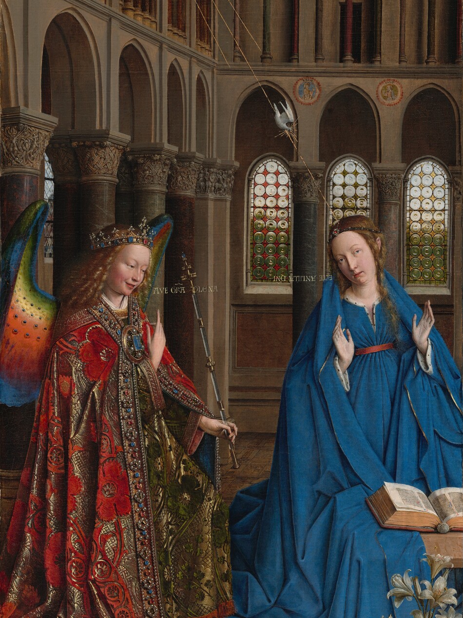 A woman and winged angel, both with pale, peach skin, are situated in a church interior in this tall, narrow painting. To our left, the angel has long, blond, curly hair, smooth skin, and is smiling. The wings are outlined in royal blue, and they blend from blue to green to yellow to crimson. The angel holds one hand, closer to us, up at chest height with the index finger subtly pointing upward. Holding a long scepter in the other hand, the angel angles their body toward the woman to our right. The angel wears a gold jewel and pearl-encrusted crown and a jeweled long, voluminous robe in scarlet-red and shimmering gold brocade. The neck and along the opening down the front are lined with pearls and jewels. The angel looks toward the woman, who wears a royal-blue dress tied with a red belt at the high waist. Her long brown hair is tied back but one tendril falls over her left shoulder, to our right. She kneels facing us with her raised hands facing outward. Her head is tipped a bit to our left, and she looks up and into the distance to our right with lips slightly parted. She kneels behind a book lying open on a low table. A vase of white lilies and a red cushion lies on the floor in front of the table, close to us. The floor is decorated with people and scenes outlined in black and set into square panels, as if inlaid with wood. The church behind and above the people has a row of tall, narrow arches with bull’s-eye glass windows. A walkway lined with columns runs above the arches, and sunlight comes in through arched windows under the flat wood ceiling. A white dove flies toward the woman on gold lines from a window at the upper left of the painting. Latin words painted in gold capital letters are exchanged between the people. The angel says, “AVE GRA PLENA.” The letters of the woman’s response are painted upside down and backward: “ECCE ANCILLA DNI.”
