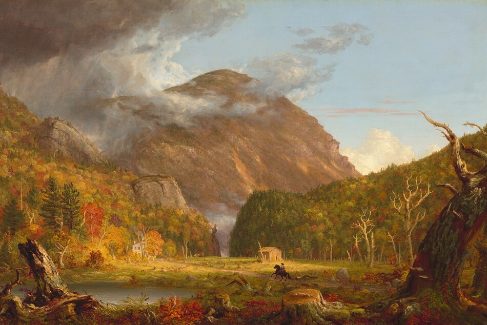 We look across a wide, low clearing at a mountain rising beyond rocky hills, which are mostly covered in pines and blazing red and orange autumn trees, in this horizontal landscape painting. The green grass of the clearing is littered with dead trees and stumps. Beyond a narrow opening between the hills, almost at the center of the composition, a massive mountain towers against the powder-blue sky, nearly reaching the top edge of the painting. The mountain’s jagged face is mottled with warm tones of cinnamon, rust, and caramel brown. The scene is bathed in warm light coming from our right but pewter-gray storm clouds move in from the upper left to encircle the mountain peak. Closest to us, a line of broken tree trunks spans the width of the painting, mixed with scarlet-red, marigold-orange, and green vegetation and reeds. A silvery pond lies just beyond them to our left. Tiny in scale within the landscape, a horse and rider gallop along a wide dirt road emerging from the lower right toward a white house nestled at the foot of the hill to our left. The rider wears a knee-length, denim-blue tunic and red leggings. Upon closer inspection, two children and a white dog become visible, walking toward the rider. A straw-yellow structure sits against the hill to our right. A horse-drawn carriage moves away from the house in the far distance, where the road curves toward the notch. The artist signed and dated the painting as if he wrote directly onto a broken trunk in the lower left corner of the painting: “T. Cole 1839.”
