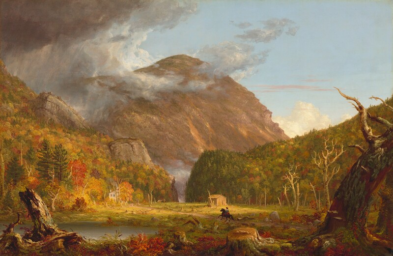We look across a wide, low clearing at a mountain rising beyond rocky hills, which are mostly covered in pines and blazing red and orange autumn trees, in this horizontal landscape painting. The green grass of the clearing is littered with dead trees and stumps. Beyond a narrow opening between the hills, almost at the center of the composition, a massive mountain towers against the powder-blue sky, nearly reaching the top edge of the painting. The mountain’s jagged face is mottled with warm tones of cinnamon, rust, and caramel brown. The scene is bathed in warm light coming from our right but pewter-gray storm clouds move in from the upper left to encircle the mountain peak. Closest to us, a line of broken tree trunks spans the width of the painting, mixed with scarlet-red, marigold-orange, and green vegetation and reeds. A silvery pond lies just beyond them to our left. Tiny in scale within the landscape, a horse and rider gallop along a wide dirt road emerging from the lower right toward a white house nestled at the foot of the hill to our left. The rider wears a knee-length, denim-blue tunic and red leggings. Upon closer inspection, two children and a white dog become visible, walking toward the rider. A straw-yellow structure sits against the hill to our right. A horse-drawn carriage moves away from the house in the far distance, where the road curves toward the notch. The artist signed and dated the painting as if he wrote directly onto a broken trunk in the lower left corner of the painting: “T. Cole 1839.”