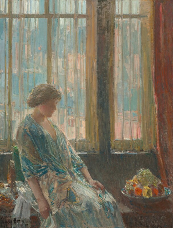 Shown from the knees up, a woman wearing an ice- and teal-blue dress and shawl sits in front of a window in this vertical painting. The scene is painted loosely with brushstrokes especially evident in the clothing and background. The woman takes up the bottom left quadrant of the composition. Her knees are angled to our right, and she looks down in that direction. She is lit from our left so her face falls into shadow, but her profile is outlined against the sheer curtains hanging behind her. Her head bows slightly, and she has rosy cheeks, a rounded nose, and her lips are closed. Her brown hair is pulled loosely back and up. Her arms lie limp, one in her lap and the other, closer to us, alongside her body. A jewel-toned blue shawl is wrapped around her shoulders over a paler, long dress. The woman sits back in a window seat or bench against a leaf-green cushion. A turquoise-blue dish on the bench to our right is piled high with yellow and red fruit and glassy green grapes. Along the left edge of the canvas, next to the woman, white streaks suggest a cloth next to a form with honey-yellow specks painted on a bronze-orange shape, perhaps a basket. Translucent yellow curtains hang across the windows, which fill the top two-thirds of the canvas. Shapes painted in shades of smoky blue and peach outside suggest buildings and skyscrapers. A russet-red curtain is pulled to the right. The artist signed and dated the lower left corner, “Childe Hassam 1912.”