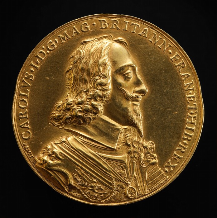 A man faces to our right in profile in low relief on this gold, round medallion. The man has heavy-lidded eyes under low brows, a slightly bumped nose, and his lips are closed. He has chin-length, curly hair, a tapered, pointed beard, and a thin mustache that points up. A high, flat collar hugs his jawline under armor decorated with stylized faces on the shoulders. A chain and pendant lies over his chest. A Latin inscription lines the perimeter: “CAROLVS I D:G MAG BRITANN FRAN ET HIB REX.” In smaller letters to the left at the start of the inscription is the artist’s name, “Briot.”