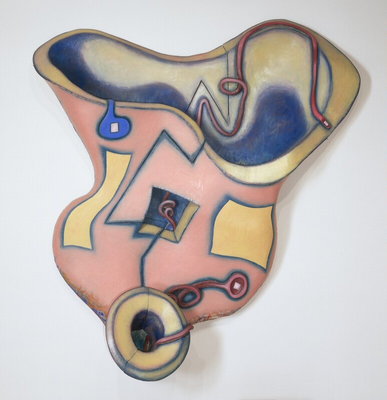 A canvas painted pale pink, straw yellow, and cobalt blue is stretched over a support shaped like a letter V with rippling sides in this abstract composition. A wobbly ring of yellow across the top suggests an opening. A red line or tube curves from the right rim to the top, and then into the vessel. The other end of the red tube coils in a tight curl and is visible through a square opening at the middle of the painting. A yellow rectangle is to the left and a yellow square to the right of the opening. Both are outlined in blue, and a blue-zigzagging line slices down the length of the painting. A hollow-centered yellow circle, also outlined in blue, is at the bottom center. After closer inspection, we find that the blue zigzagging line appears to be a cut separating the two halves that fit together like puzzle pieces.