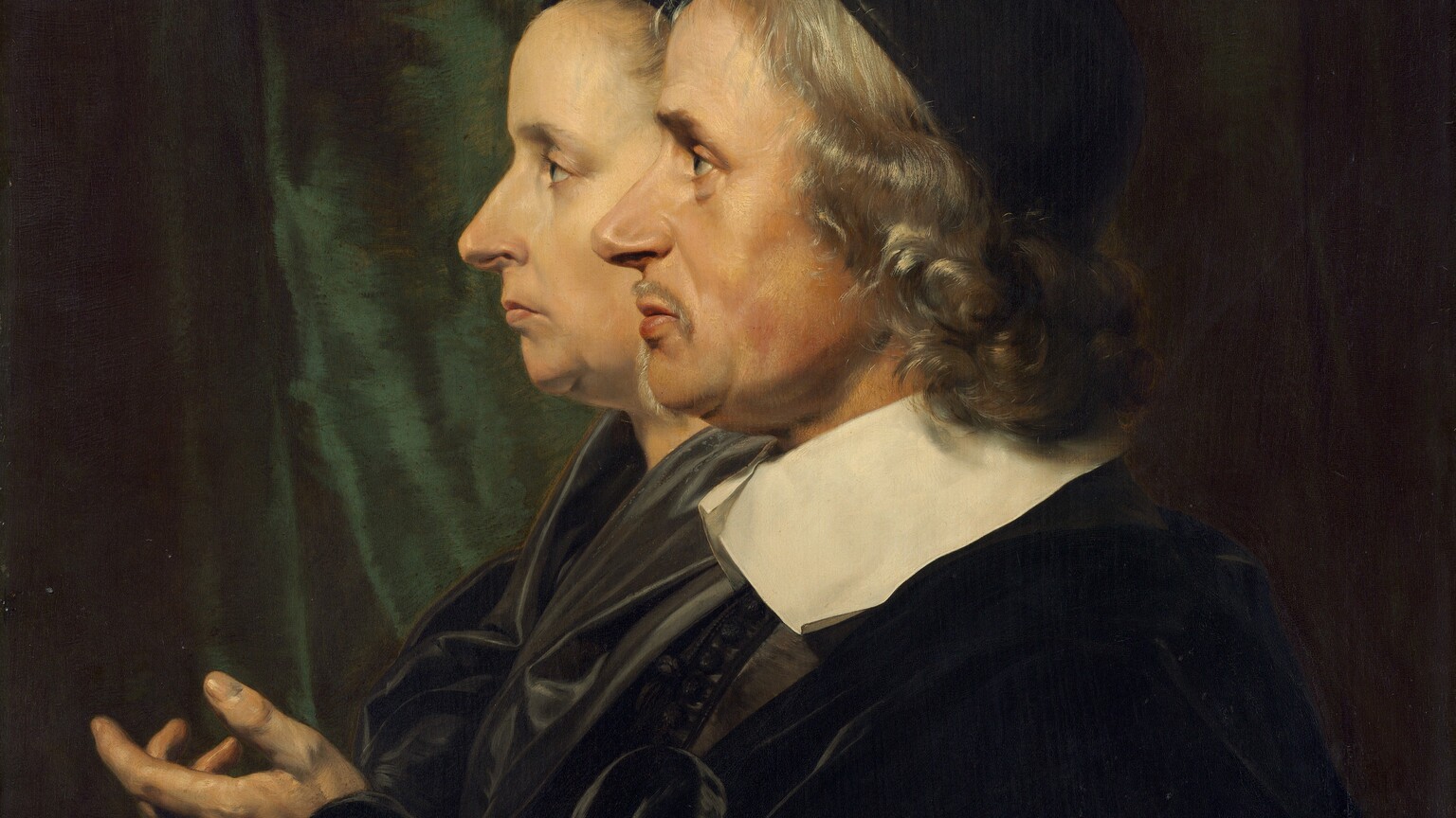 Shown from the shoulders up, a man and woman face our left in profile against a shadowy, dark green curtain in this vertical portrait painting. They both look steadily to our left, they and have pale skin and wear black. The man is closer to us so he overlaps the woman, whose profile is shifted to our left. A black cap sits on the man's curly, silver, shoulder-length hair. He has a slight double chin and soft jowls. A thin mustache curves over his upper lip, and a line of hair runs down his chin as a narrow beard. A broad, flat, white collar lies across his shoulders over a velvety black coat. He lifts his left hand, closer to us, in front of his chest with the fingers curled gently inward. The woman also has a double chin and soft jowls. Her thin lips are closed and downturned. Her hair is pulled back under a black covering, and her black garment has a sheen, suggesting satin.