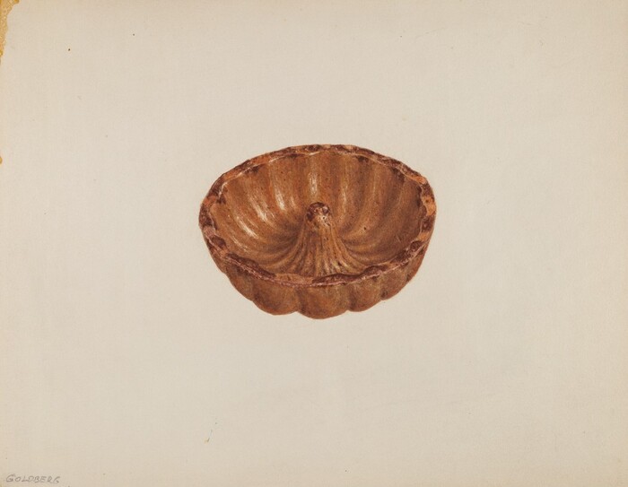 The image shows a fluted mold or bundt pan in the center. The color palette consists of warm brown and golden hues. The mold is in focus, displaying its detailed texture and shape against a light background.