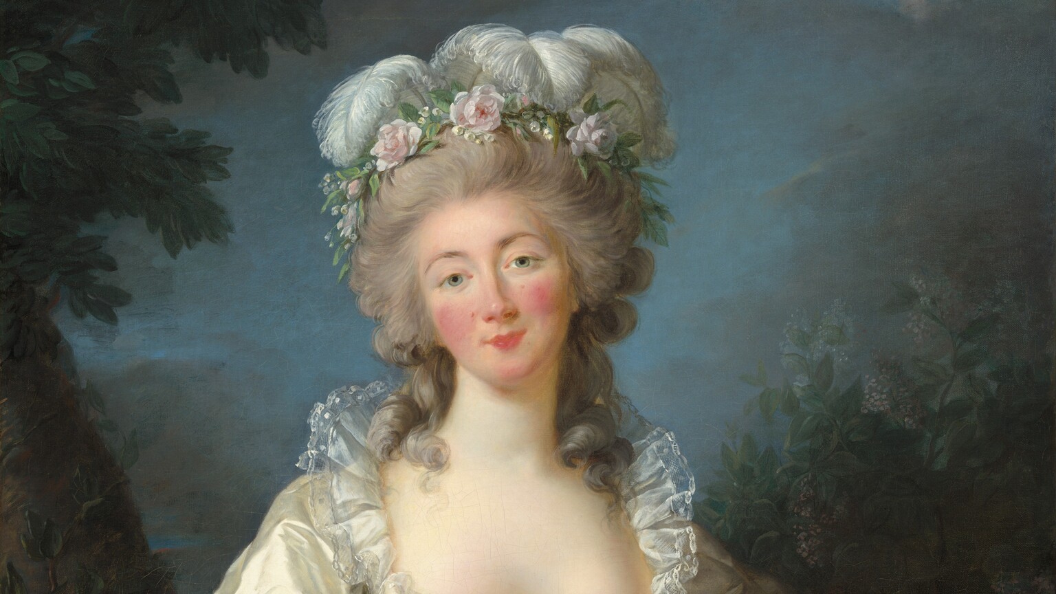 Shown from the knees up, a woman stands facing and looking at us with her head tilted a little to our left in this vertical portrait painting. She has pale skin, a heart-shaped face with rosy cheeks, and a rose-pink bow mouth. Thin, arched, sable-brown eyebrows frame her gray eyes. A wreath of pale pink flowers and curling white ostrich feathers crowns her long gray hair, which is piled high on her head. Loose curly tendrils brush both shoulders. Her glowing, silver satin gown is trimmed with delicate sheer lace around the wide, plunging neckline and sleeves, and has a pink sash around her narrow waist. Pearl bracelets adorn her wrists. She leans to her left, our right, to rest her left elbow against a waist-high, cinnamon-brown stone pedestal, which is decorated with a bronze-colored garland and bow on the side facing us. A ring of blue, yellow, red, and pink flowers, woven with strands of ivy, dangles in the hand resting on the pedestal. Her right hand hangs loosely by her side. Along the left edge of the dimly lit background, a tree with a thick trunk angles into the upper left corner. A smaller sapling grows just in front of it. On the right, bushes with olive and fern-green leaves dotted with lilac-purple flecks rise above the pedestal. Dark clouds fill most of the top third of the canvas but they part around her head to reveal the soft blue sky. The artist signed and dated the work in white in the lower right corner, “L. Vigée Le Brun 1782.”