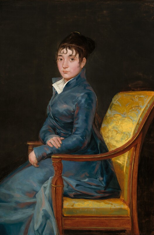 Shown from the knees up, a pale-skinned woman wearing a muted, sapphire-blue gown sits ramrod straight in a chair and looks at us in this vertical portrait painting. The chair and the woman’s body face our left in profile, but she turns her round face to look at us with large, light brown eyes. She has slightly flushed cheeks, a straight nose, a full lower lip, and her mouth is closed. Her left forearm, closer to us, rests on the front corner of the wooden arm of the chair. Her other hand lies across that forearm. Her blue dress has a high collar and wraps closed across her chest. The full skirt bunches around the back of the seat and around the arm of the chair. The corners of a white collar lie open at the woman’s throat, nestled into the dress's lapels. The dress is painted rather loosely with shades of slate and royal blue and shaded with mauve pink, giving it a hint of a sheen. The back and seat of the wood chair is upholstered in gold-colored fabric, which is also loosely painted with the suggestion of a brocade pattern. The background is dark brown, nearly black.