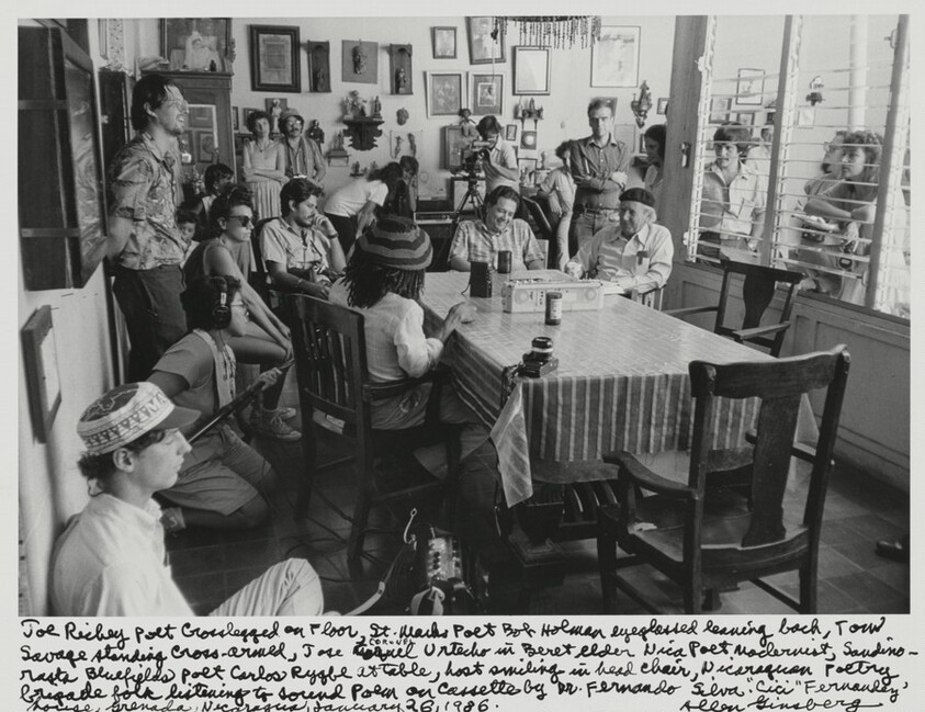 Joe Richey poet Crosslegged on Floor, St. Marks Poet Bob Holman eyeglassed leaning back, Tom Savage standing cross-armed, Jose CORONEL Urtecho in Beret elder Nica poet modernist, Sandinista Bluefields poet Carlos Rigby at Table, host smiling in head chair, Nicaraguan Poetry brigade folk listening to sound poem on cassette by Dr. Fernando Silva, "Cici" Fernandez' house, Granada, Nicaragua, January 26, 1986.