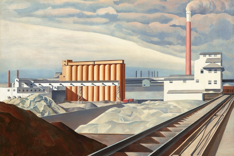 This nearly square painting shows an industrial area with buildings, storage silos, a smokestack, and railroad tracks. A mound of brown dirt or other material is in shadow in the lower left corner of the painting. Next to the mound, railroad tracks extend diagonally from the lower center of the painting into the distance to our right. The tracks end at a white building with staggered gray rooflines to our right in the distance. A tall terracotta-red smokestack rises high beyond the white building, smoke pouring out of its top and blending into the clouds above. Just beyond the mound of dirt, piles of white material, perhaps in unseen bins, line the railroad track to our left and lead back to a row ten interconnected, coral-orange silos. The horizon comes about halfway up the painting, and it is lined with a row of long white and gray warehouses. The artist signed and dated the work with brown paint in the lower right corner: “Sheeler 31.”