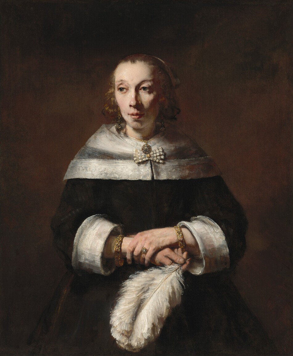 A woman with pale skin, wearing a black dress and holding a full, billowing white ostrich feather, is shown from the hips up against a dark background in this vertical portrait painting. She has dark eyes, faint, arched brows, a slightly pink nose, and her pink lips are parted. Light falls from our left, creating shadows under the other cheekbone and along the side of her neck. Her shoulders are covered by a transparent, white, lace-edged wrap fastened with a bow. Her black dress also has wide, white cuffs, exposing a thick, possibly jeweled bracelet on each wrist. She wears two gold rings, one with a clear gem, perhaps a diamond, gold, dangling earrings, and a round pendant necklace. The lush white ostrich feather arches down from her right hand, held at her waist by her opposite hand, clasping that wrist.