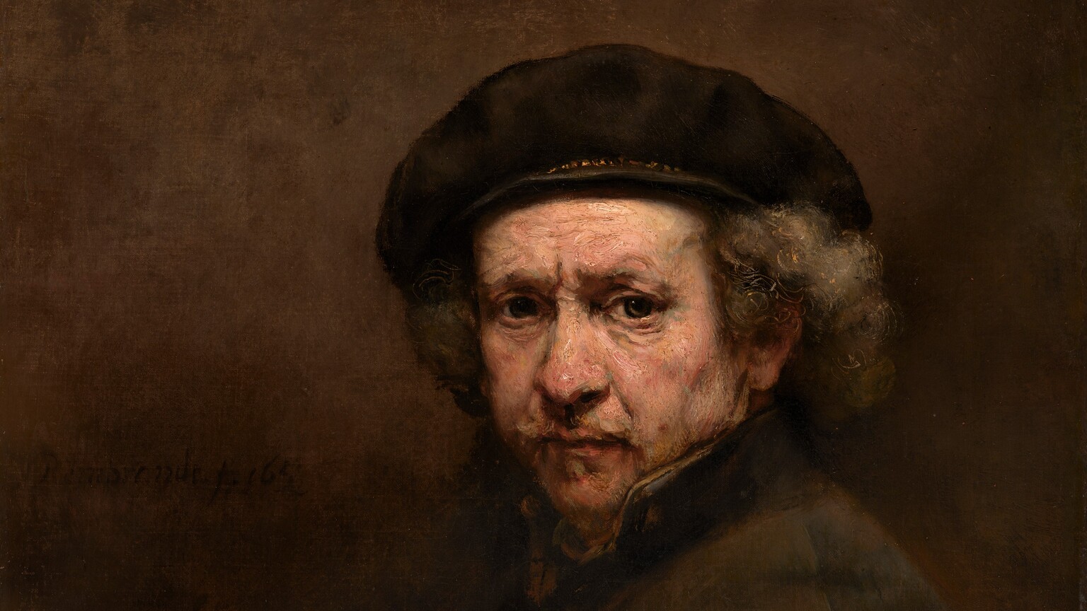 Shown from the waist up, an older man with pale, peachy skin looks out at us with deep-set, gray eyes under a furrowed brow, in front of a sable-brown background in this vertical portrait painting. His body is angled to our left, and his face turns to us. He has a faintly pink, bulbous nose, and his slightly sunken cheeks are shaded with gray. His peach-colored lips are framed with a wispy, gray mustache and goatee. Bronze-orange lines are incised within the battleship gray of his hair to create soft curls under his brown beret, which has gold trim around the base. The dark collar of his fawn-brown coat is turned up so his neck is covered. He is lit from the upper left, so his body and the right side of the painting are deeply shadowed. On our left, the canvas is painted with blended strokes of tawny and dark brown. His dark coat blends into the background, and his folded hands are in shadow in the lower left corner. The brushstrokes are visible in some areas, especially in the man’s face. The painting is signed and dated next to his shoulder, to our left, “Rembrandt f. 1659.”