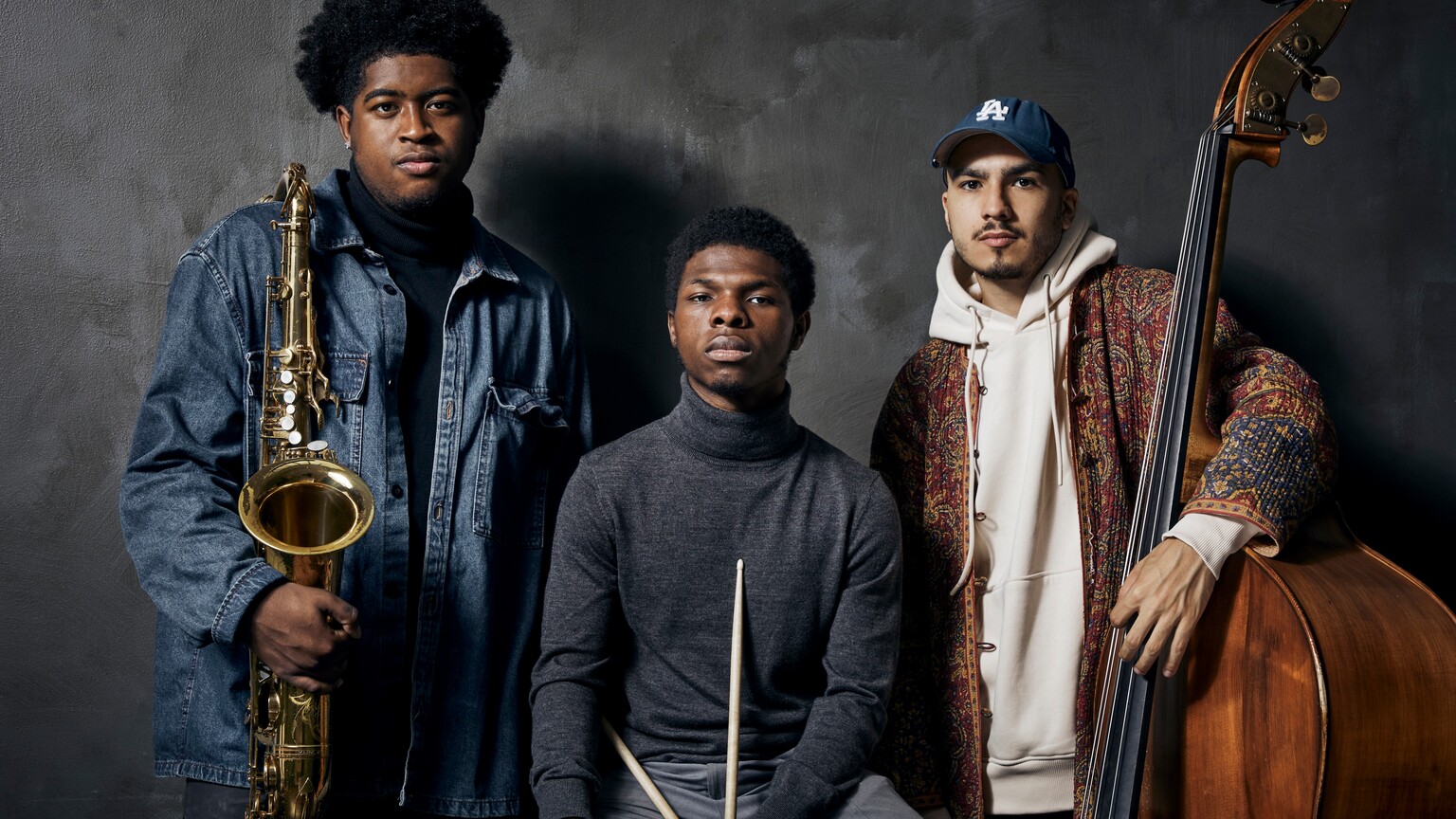 A band, made up of three young men, holding their instruments.