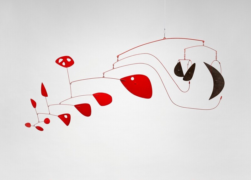 This free-floating sculpture, called a mobile, hangs from the ceiling. Thirteen flat, uniquely shaped paddles are suspended on curving, painted wires in bowing, branch-like forms. Three black crescent shapes hang to our right in this photograph. Ten crimson teardrops, ovals, and rounded triangular forms float in two tiers in an arc that descends gently to our left. The red shapes get smaller as they move away from the black forms. Three of the red shapes are pierced with holes.