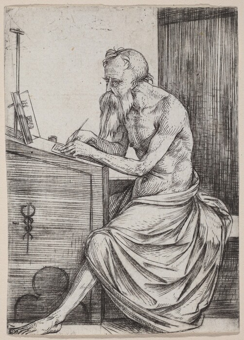 The image shows a man seated at a writing desk. He is in profile, leaning forward with his right hand holding a pen and his left hand resting on the desk. The man has facial hair, a receding hairline, and short hair on top with a fuller back. He is draped with cloth, exposing his upper body and right leg. The desk is cluttered with papers, an open book, and an ink pot. A staff or pole leans against the desk. The background has linear textures, suggesting a wall or a partition.
