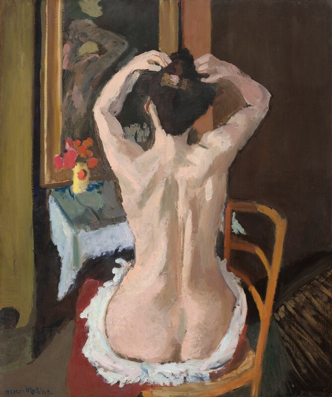We look slightly down onto a nearly nude woman with pale pink skin, who sits facing away from us as she lifts her hands to her dark hair in this vertical painting. The scene is painted with broad, visible strokes, and some details are difficult to make out. The woman's torso and head almost fill the vertical height of the painting. The scene is loosely painted so some details are indistinct, but she seems to face a mirror above the small table of a vanity. Visible brushstrokes in tones of pale peach and pink, taupe, and faint sage green capture her spine, shoulder blades, the muscles of her arms, and the dimple above her round buttocks. She uses both hands to pin up her chestnut-brown hair above a rectangular clip painted in muted gold with touches of light pink. She sits sideways in a wooden chair so the ladder-back is to our right. Her thighs are wrapped in a fluffy white piece of cloth, perhaps a towel, which may be wrapped with a ruby-red cloth or it could be a red cushion beneath. The surface of the narrow tabletop in front of her, to our left, is painted with areas of sage green, elephant gray, and royal blue. About a dozen orbs in coral orange and fuchsia pink above and around a band of canary yellow suggest flowers in a yellow vase along the left side of the table. The mirror above the vanity has a wide, gold frame. The woman’s reflection is painted with long strokes of ash brown with a few touches of rose pink. Though abstracted, the reflection seems to capture her torso and one bent elbow. The wall to our left of the vanity is pale pea green and to our right, dark brown. Streaks of honey-brown against a black field in the lower right corner suggests an area rug on an otherwise peanut-brown floor. The artist signed the work in marine blue in the lower left corner, “Henri Matisse.”
