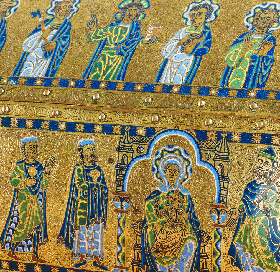 A free-standing, gold, enameled, rectangular box has a triangular top like the roof of a house, and the box rests on a short, square foot in each corner. In this photograph, we look onto one long side and the short side to our right is angled toward us, so we see the panel there, too. Along the long side, five people are shown from the waist up in the upper, roof-like panel and six more line up on the panel below. The skin of every person is gold, and all wear robes and garments in lapis or sky blue, spring green, yellow, and white. The area around the people is also gold, and each panel is encased by a royal-blue band dotted with stylized stars at regular intervals. Each panel is then lined with small, button-like rounded bosses around its edges. In the upper panel, all of the men except the second from the right have beards, and all have halos with wavy bands of blue, green, yellow, and white. The man to our left holds a book and his neighbor a skeleton key the length of his arm. The man at the center holds up a book with his left hand, on our right, and raises the index and middle fingers of his other hand, held up at shoulder height. The two men to our right also hold books. In the panel below, three horses’ heads peek in from the left edge, creating a vertical band, and three crowned men line up, holding gold vessels and looking toward a woman seated in a throne with a child on her lap. The woman has a halo made with a wavy pattern of blue, yellow, green, black, and white. Her throne is flanked by columns, and the area around it is edged with bands of white, light, and dark blue. The baby wears gold, has a halo, holds a book in his lap with his left hand, and raises the first two fingers of his other hand toward the three men. The final person in this panel wears a hat, holds a scepter topped with a fleur-de-lis, and gestures at the woman and baby. The head and shoulders of a haloed person is visible along the short side of the box, which is angled sharply away from us. The gold between all the people and bordering each panel is intricately carved with tiny flowing organic lines and swirls.