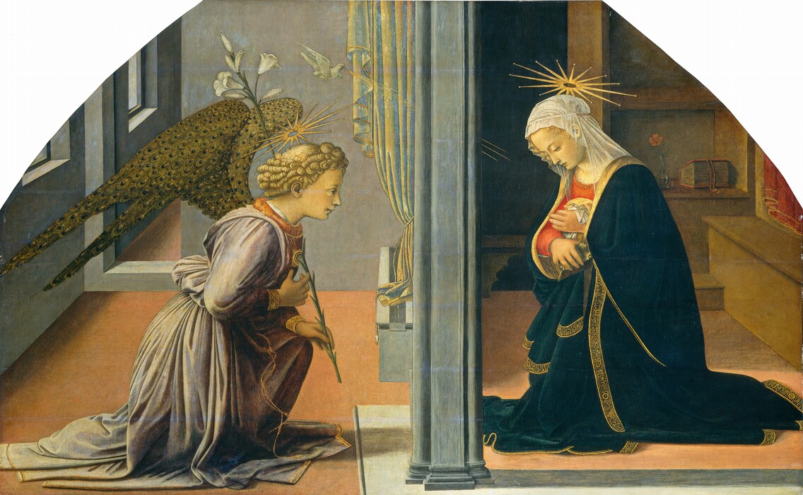 Separated by a vertical, column-like partition, a woman to our right kneels opposite a winged angel to our left, who also kneels and holds the stem of a long white lily propped against one shoulder in this horizontal painting. The upper corners are curved, suggesting the panel was set in an arched frame. Both people have pale, peachy skin with a yellow cast, delicate facial features, and starburst-like gold halos hovering over blond, curly hair. To our left, the angel faces our right in profile, one hand held to the chest as the other, resting on the raised knee, holds the stem of the lily. The angel wears a voluminous, lavender-purple robe tied in pleats at the waist with a gold cord. The neckline is marigold orange, and the cuffs and hem are edged with gold. The wings emerging from the shoulder blades are made of rounded, gold and blue feathers like the eyes of peacock feathers. A white dove hovers above the angel’s head and gold rays extend toward the woman, to our right. The woman kneels, facing our left in profile, her head bowed. A gauzy white head covering is tied around her hair. She holds the sides of her deep blue robe at her chest, over a coral-red dress. The hem of the blue robe is edged with gold lettering resembling writing. She clutches a small, thick book with a teal-blue cover and gold edges in one hand at her chest. The angel and woman are separated by a slate-gray, column or partition, and the room behind each person is slightly different. The angel is set in a room with stone-gray walls with a doorway on the back wall, and rectangular openings on the wall to our left. The salmon-pink floor spans both rooms, but is banded with gray along the bottom edge of the painting to our right. The woman is in a room with a bench and shelves holding a thick book and a pink flower in a glass vase. A darkened doorway opens, presumably into another room, opposite us. A curtain hangs down along the partition in front of the angel, perhaps indicating that a window separates them. The rays emanating from the dove also disappear behind the partition to reemerge on the other side, suggesting a window.