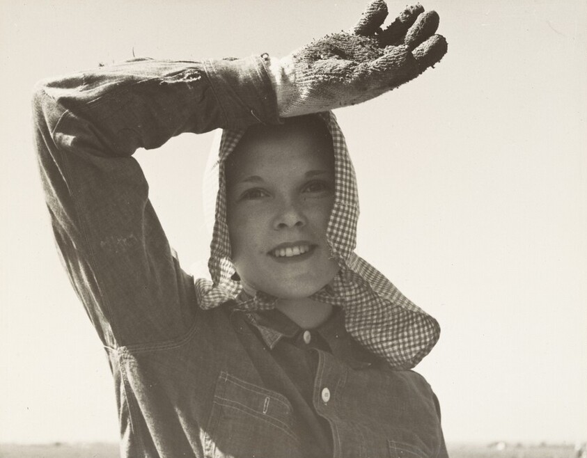 Young girl looks up from her work. She picks and sacks potatoes on large-scale ranch, Edison, Kern County, California