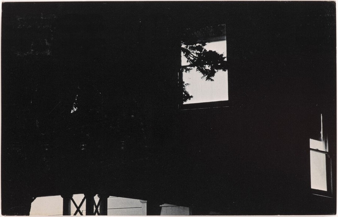 The image shows a composition of dark and light shapes with angular lines and rectangles resembling windows. A large dark silhouette surrounds lighter rectangular patches that resemble windows with light shining through. One rectangle is framed by branches, resembling a tree outside a window, while a smaller rectangle in the lower right corner also suggests a window, reinforcing the architectural theme.