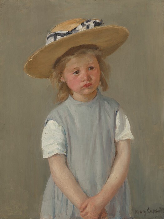 Shown from the waist up, a young girl wearing a slate-gray dress and straw hat stands with her hands clasped in front of her in this vertical portrait painting. The girl has light, peachy skin, and her cheeks are lightly flushed. Her body faces us but she tips her head slightly to her right, our left, and looks off into the distance with dark brown eyes. Her faint eyebrows drawn together, and her cherry-red, full lips slightly turn down at the corners. She has a button nose and a rounded chin line. She has dark blond, straight, shoulder-length hair under a wide, flat-brimmed straw hat. The hat is wrapped around the crown with a checkered white and black bow. Her shoulders slope down as she holds one wrist with the other hand down in front of her. She wears a jumper over a shirt with short white sleeves. At first glance the jumper appears pale gray but closer inspection reveals strokes of pale lilac, ivory white, and cobalt blue. The girl’s features and clothing are painted with loose, visible brushstrokes, and the background behind her is painted with vertical strokes of tan blended with faint green. Short dabs of brighter gold and butter yellow give the impression of sunshine on the brim of the hat and in the girl’s hair. The artist signed the work with loose letters in the lower right corner, “Mary Cassatt.”