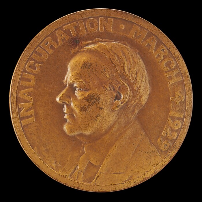 The image depicts a sculpture in the form of a medallion featuring the profile of a man's head, sculpted in relief. The subject is depicted with neatly combed hair and dressed in a coat and tie. The sculpture is made from a material that suggests a metallic composition, with a golden-brown color dominating its appearance. Engraved text around the edge of the medallion reads "INAUGURATION MARCH 4, 1929." The sculpture is intricately detailed, capturing the facial features and attire of the subject with precision and depth relative to the flat surface of the medallion.