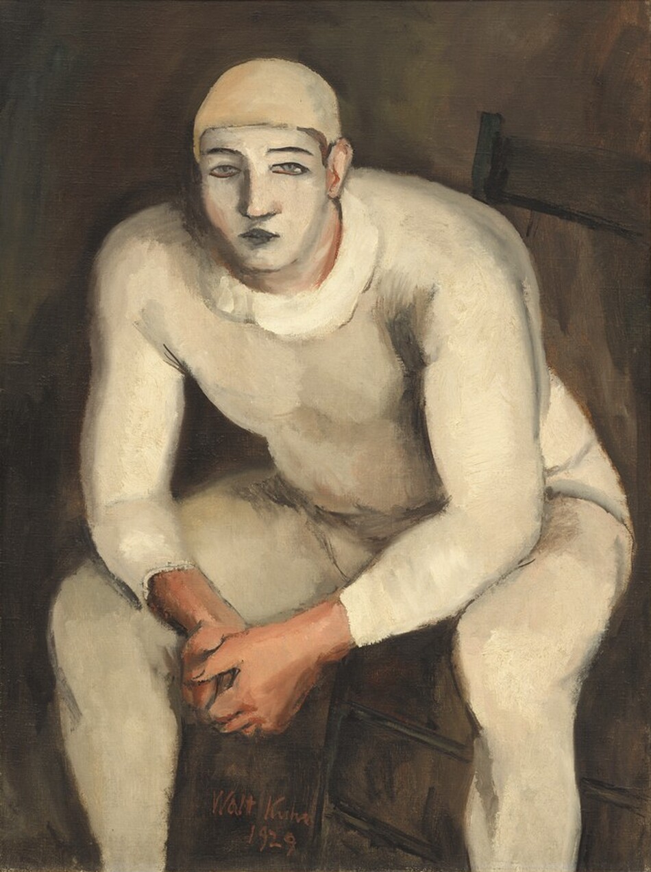 A stocky, muscular man with his face painted white and wearing a skin-tight, oyster-white costume sits on a wooden chair, leaning forward toward us with his elbows resting on his knees in this vertical painting. The man nearly fills the canvas, and his feet are cropped by the bottom edge. His body is angled slightly to our left with his knees spread wide, but he looks out at us. He wears a pale, beige-colored cap and his cream-white bodysuit may have a loosely painted, wide collar. His nearly straight eyebrows and closed lips are painted black, and his narrow gray eyes are outlined in black, against the white oval of his painted face. His clasped hands, ears, and his skin visible along the edges of his makeup are pale peach. The background is earth brown. The artist signed and dated the work with red paint between one of the man’s legs and the leg of the chair, near the lower center: “Walt Kuhn 1929.”