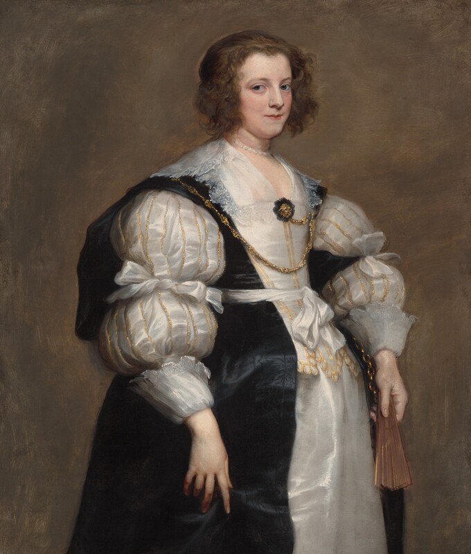 Shown from the knees up, a pale-skinned woman wearing a voluminous, gold-trimmed, white satin gown and a black overdress stands holding a closed fan in this vertical portrait painting. Her body and face are angled to our right, and she looks at us from the corners of her gray eyes. She has pale skin, a straight nose, thin lips, and a slight double chin. Chin-length brown waves frame her face, and the rest of her hair is pulled back. A pearl necklace lies at the base of her neck, though traces of another necklace, originally painted higher up on the neck like a choker, are visible. A lace-edged collar lies along her shoulders, and more lace lines a kerchief tucked into the low, straight neckline of her bodice. The gown’s puffy sleeves are tied around the elbows and end in wide lace-lined cuffs at the wrists. The sleeves and the front and bottom edges of the bodice are lined in glittery gold. A bejeweled gold brooch nestled in black lace is pinned to the front of her gown. A gold chain links the brooch to one side of the bodice before draping across her chest and lying over the other shoulder. A white satin ribbon is tied with a bow around her waist over the black overdress, which has subtle suggestions of a black-on-black pattern down the front. The fan is in her left hand, to our right, perhaps attached to a length of gold chain visible under her wrist. Her other hand rests in the folds of the black overdress. Some brushstrokes are visible in the woman’s clothing and in the walnut-brown background.