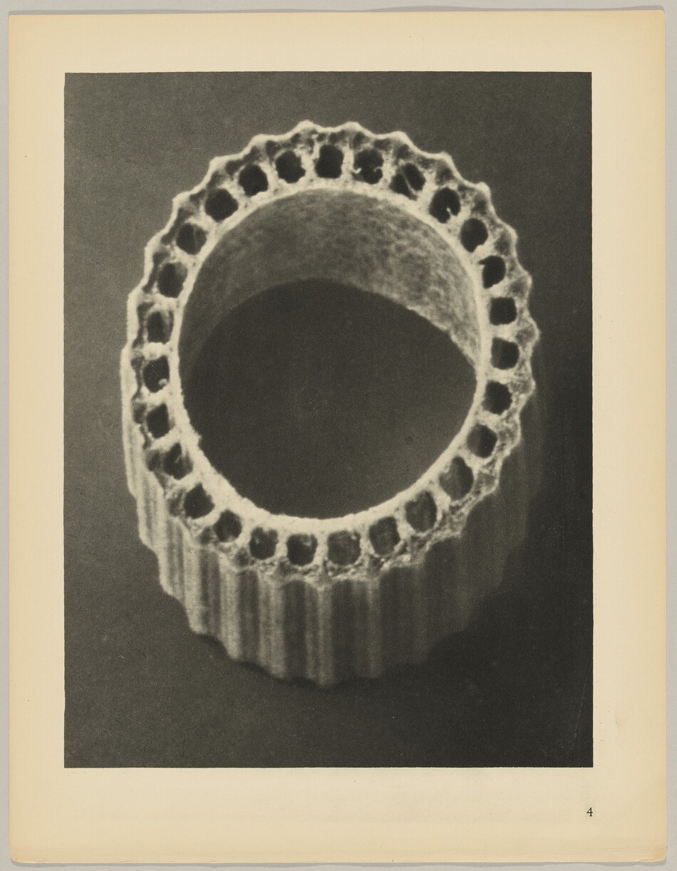 The image shows a circular, ribbed tube-like object with scalloped edges and multiple evenly spaced holes along the top edge. The color palette is monochrome, varying in shades of gray. The object is centrally positioned, symmetrical, and occupies a significant portion of the image. The background is a solid darker gray, contrasting with the lighter color of the object. The image is set against a lighter border with a page number '4' at the bottom right corner.
