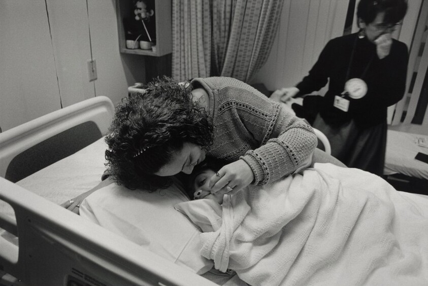 Boston (Sharon Morrison, a nurse with the Family Team at Boston Health Care for the Homeless Program, has a special fondness and respect for this young mother and her daughter. She marvels at the calm and loving manner of the mother and the corresponding spirit of joy and playfulness in her child. The little girl is about to undergo emergency brain surgery to replace a shunt.)