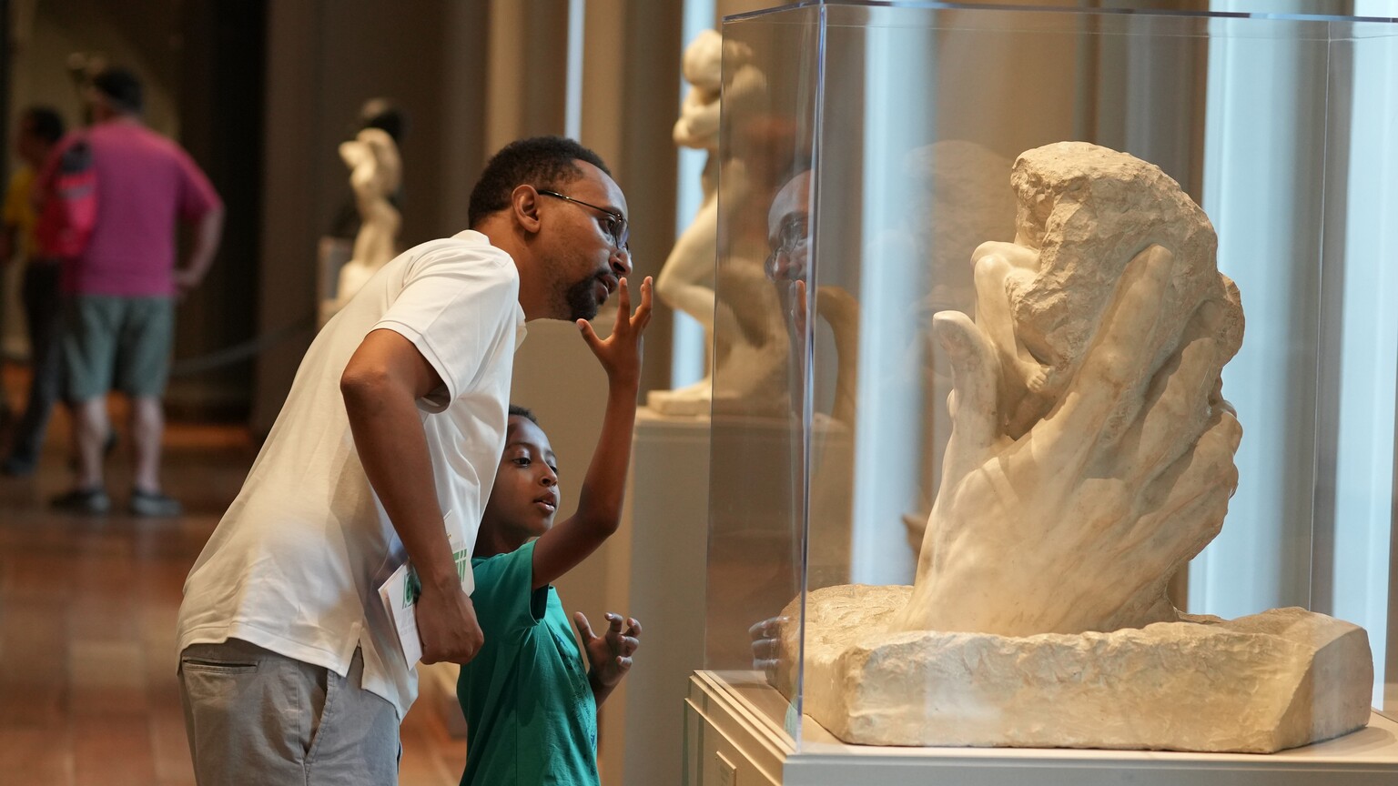 A man and a child looking at a sculpture in the National Gallery of Art.