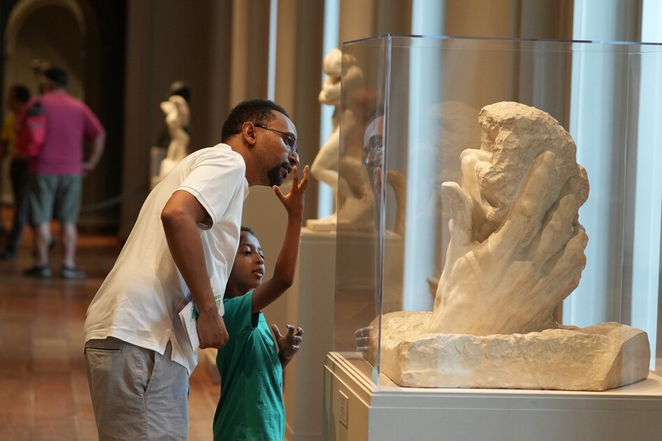 A man and a child looking at a sculpture in the National Gallery of Art.