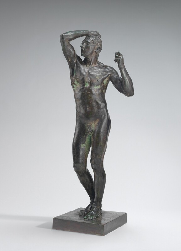 This free-standing, bronze sculpture shows a nude, muscular, young man standing with his right hand, to our left, raised to the top of his head. In this photograph, his body faces us but his head turns slightly to our left toward the raised hand. He stands on a square base with his feet together and his right knee, on our left, slightly bent. That arm is raised in front of him with the elbow bent back so his hand grasps his short hair. His eyes and full mouth are closed. His other arm is also bent at the elbow at his side so that hand is at shoulder level, his fist curled. The dark gray bronze has a green patina in some areas, especially along the ribcage, the inner thighs, and the top surface of the raised arm.