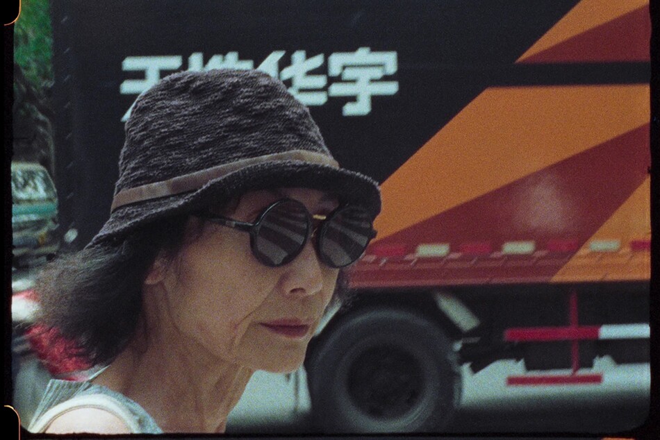 A woman wearing a hat with a circular brim and round sunglasses.