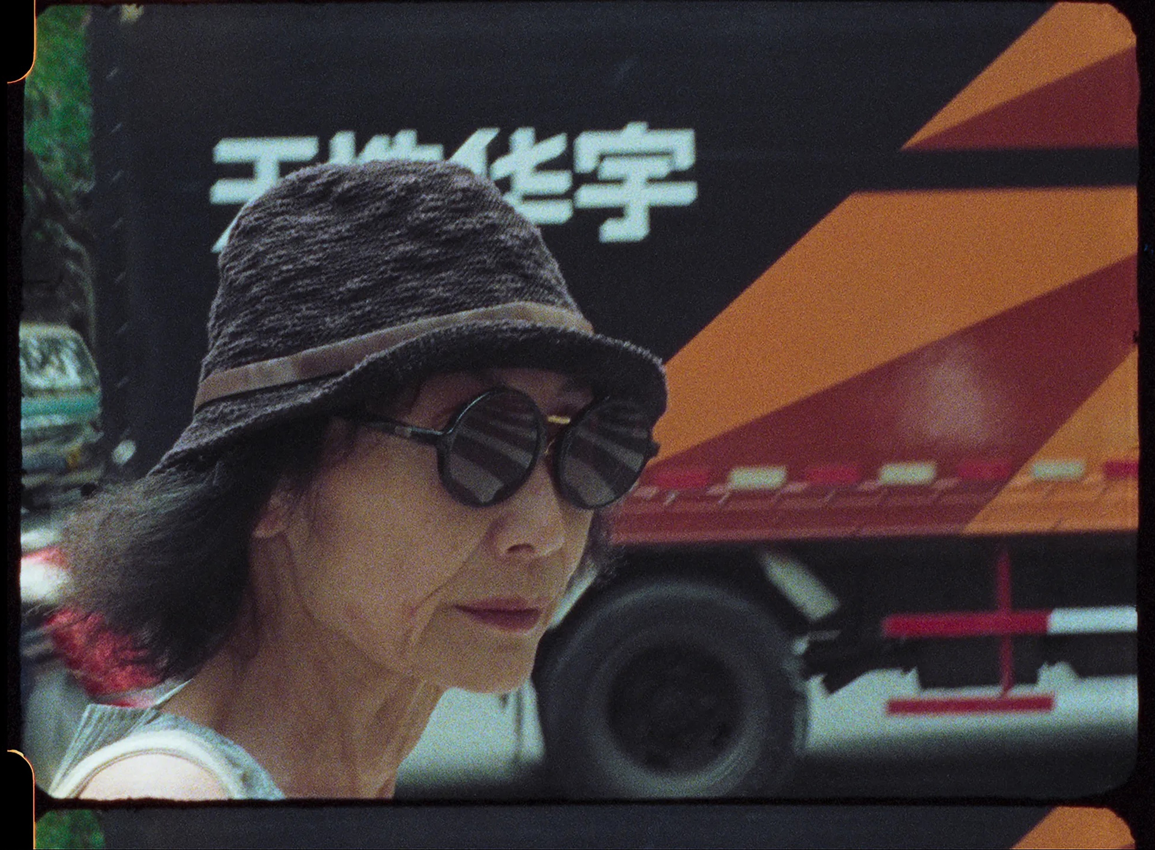 A woman wearing a hat with a circular brim and round sunglasses.