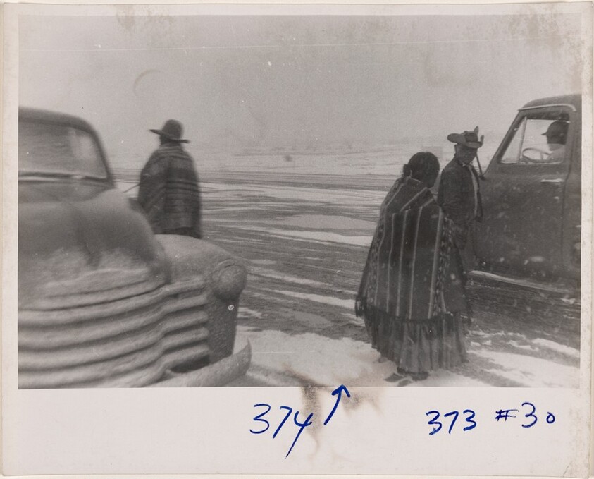 Three figures beside two trucks in snow--New Mexico