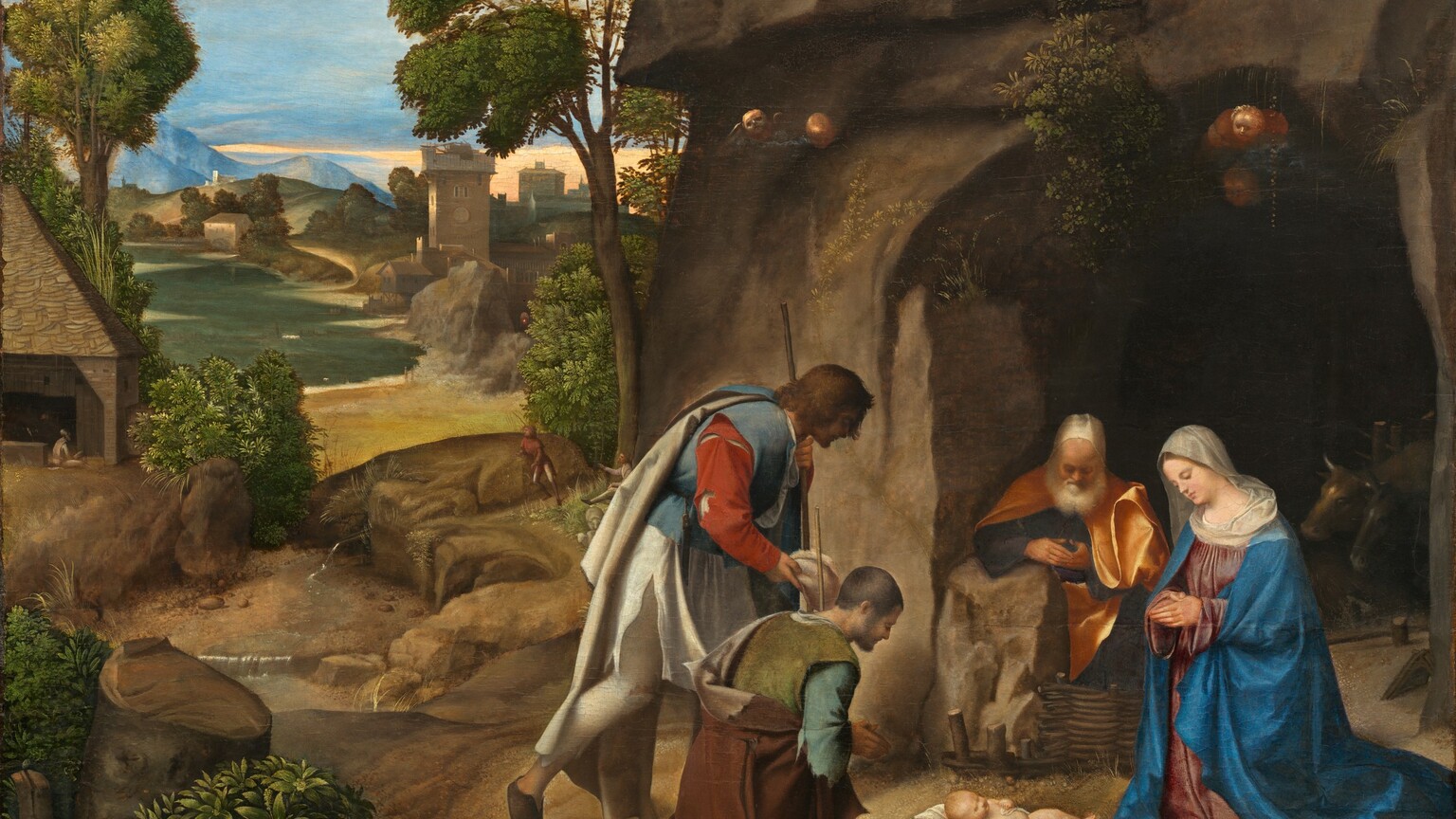 Four people with pale skin are gathered to our right in a landscape, their heads bowed down toward an infant who lies on a white cloth on the ground in this horizontal painting. The nude baby has a rounded belly, chubby limbs, and short blond hair. To our right and near the edge of the panel, a woman kneels with her hands in prayer, looking toward the baby so she faces our left in profile. She wears a lapis-blue robe over a rose-pink dress, and a white cloth covers her head and shoulders. Behind her and to our left, a man with a white beard, wearing a golden yellow robe, sits or kneels next to a rock at the mouth of a cave cut into a rocky outcropping that extends off the top of the composition. To the left of the baby and at the center of the foreground, a pair of men wear tattered clothing and hold shepherd’s staffs. The man closer to us kneels with his hands pressed together in prayer as the man behind him bends his knee as if to kneel. The landscape recedes deep into the distance on the left half of the painting with a winding river, houses and other buildings, grassy hills, and mountains beneath a blue sky. A small winged angel wearing white looks down on the scene from the upper left corner.