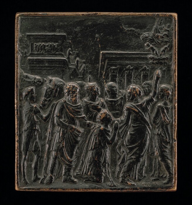 This is a square plate carved in relief, depicting multiple people gathered in a group. In the center, a person kneels, looking up at a person on the right. The person next to them is standing, gesturing upwards to the top right corner, where swirling clouds and small cherubs seem to appear in the sky. Some of the other people in the crowd look up as well. The people all appear to wear draped robes. One person on the left tends to two horses. There are architectural elements in the background, including columns topped with statues. The sculpture is primarily a dark, metallic color, with some light brown areas.