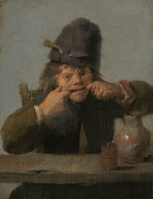 A young man with tanned, peachy skin sits at a table pulling his mouth wide with both hands in this vertical painting. On the far side of a wooden table, he faces us with elbows splayed wide. He has hooked the first finger of each hand into the corners of his mouth to stretch his open lips into a long, goofy line. He has wide-set eyes and a wide nose. His brown hair sticks out from under a tall, fuzzy brown hat, which has a knife secured by the blade in a loop to our left. The man’s iron-gray jacket has coffee-brown sleeves with the white of his shirt showing at the cuffs. A putty-gray jug accented with washes of rust-red and a glass filled with an amber liquid sit on the table before him. Soft light from the upper left gleams white on these smooth surfaces. A dark mass visible under the table is presumably the tops of his legs. The top right corner of his wooden chair is visible over his right shoulder, on our left, and he is set against a dove-gray background. The scene is loosely painted so brushstrokes are especially visible in the man’s face and hands.