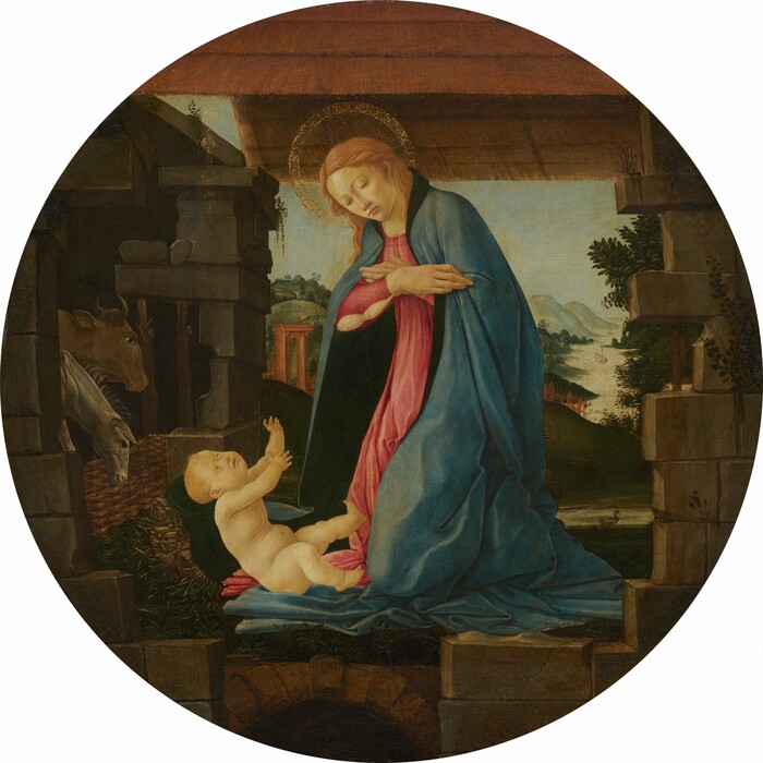 A woman kneels, angled to our left, and tips her face down toward a naked baby propped on a pillow against a pile of hay in a shed-like structure in this round painting. The woman and baby have pale skin, blond hair, and their heads are surrounded with gold halos. The woman’s arms cross her chest as she looks down, her eyes nearly closed. She has high cheekbones, a narrow chin, a long, straight nose, and her pale lips are closed. Her long hair tucks under the neck of her aquamarine-blue cloak, which covers her coral-red dress. The dress and robe pool around her legs and under the baby, near her knees to our left. The baby has rounded cheeks and his belly and legs are pudgy. His hands and arms stretch up to the woman and his head is tilted dramatically back to look up at her. One foot, farther from us, kicks out and the other knee is bent. The woman and baby are on a grassy area supported and framed by concrete-gray blocks, over an arched doorway below. The stone blocks also enclose an area housing a donkey and ox to our left. There is a thatched roof above and a landscape with rolling hills and a river beyond.