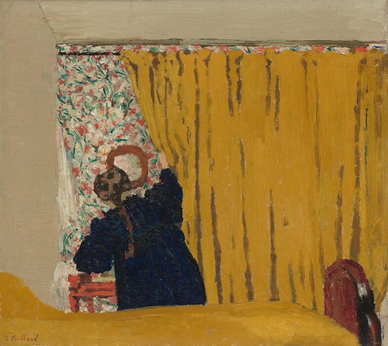 A woman pushes aside a deep golden yellow curtain that fills three-quarters of this nearly square painting. The curtain runs on a rod parallel and close to the top of the canvas, extends off the right edge, and falls behind a bed covered in the same color. The bed is cropped by the bottom and left edges of the painting, and a brown, arched wood footboard almost reaches the right side. The woman stands on the far side of the bed, facing away from us as she pulls at the curtain with her right hand. She wears a navy-blue dress and a brown braid falls down her back. She reveals an area covered in a pink, green, and white floral pattern that seems to match the size of the curtain, at least along the left edge where it is exposed. A round mirror hangs on the floral-patterned area above a red piece of furniture, perhaps a small table or stool. The wall around the patterned area and curtain is painted bone white. A line incised in the paint running from the top left corner of the floral area to the top edge of the canvas suggests a crack in the wall. The paint is loosely applied so brushstrokes are visible throughout, especially in the floral pattern. The artist’s signature is painted in red in the lower left corner: "E. Vuillard."