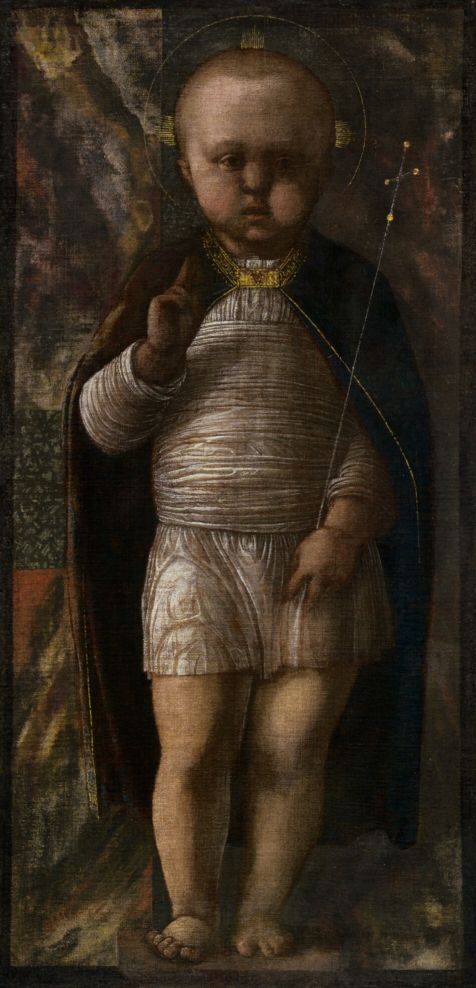 Nearly filling this vertical painting, a young, light-skinned child stands with a delicate scepter tucked into one elbow as he holds up his other hand with the first two fingers raised. The child is lit from our left, but the overall tone of the painting is shadowy and dark. His body faces us, and he looks off to our right with round, deeply shaded eyes. He has short blond hair and a tall forehead, chubby cheeks, and his bow lips are parted. Short, gold rays emanate from the sides and top of his head within a thin gold band to create a halo. He wears a thigh-length, white tunic, and more of that fabric is wrapped around his torso. His dark, burgundy-red cape falls open across his shoulders and down to his calves, and is edged with gold around the collar and down the front. A rectangular, jewel-encrusted gold clasp holds it closed at the throat. He stands with most of his weight on his left leg, to our right, on bare feet. His right hand, to our left, is raised to his chest with the first two fingers extended up. The delicate silver scepter he holds with his other hand is topped with a cross. Swirling patches of muted brick red, harvest yellow, pine green, and off white behind him could be a tapestry. A thin, dark band creates a border around the edges of the painting.
