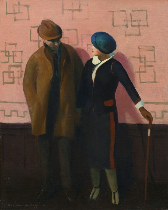 A man and woman stand against a wall with dark brown wainscoting and rose-pink wallpaper in this vertical painting. Both people have pale, peachy skin and wear hats that hide their eyes. The man is to our left and wears a brown fedora and a thigh-length, brown coat over a dark suit. He appears to look down at the woman’s body with his head tipped toward us. His right hand, to our left, is in his coat pocket. The woman’s right arm, to our left, overlaps the man’s other arm. The woman is shorter than the man but stands with her shoulder almost touching his arm. Her left arm, to our right, is stretched out and that gloved hand rests on the head of a cane. Shown in profile, the woman looks at the man’s face. She has a delicate nose, and her small red lips are closed. Her shirt has a round collar that lifts off her shoulders. She wears a navy-blue jacket with brick-red piping and a blue, shin-length skirt with a red stripe down the side. Her stockings are sage green, and she wears dark, T-strap shoes. The pink wallpaper behind them is loosely patterned with overlapping olive-green-outlined boxes. The artist signed and dated the lower left corner, “Guy Péne du Bois 22.”