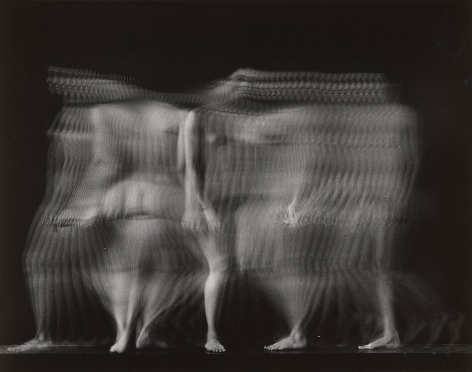 The image shows wavy, horizontal lines creating an abstract depiction of a human figure in motion. The blurred lines and overlapping contours resemble ripples of water, suggesting movement and fluidity. The composition suggests a person walking, similar to a time-lapse photo with multiple overlapping images creating a ghost-like figure in a dark space.
