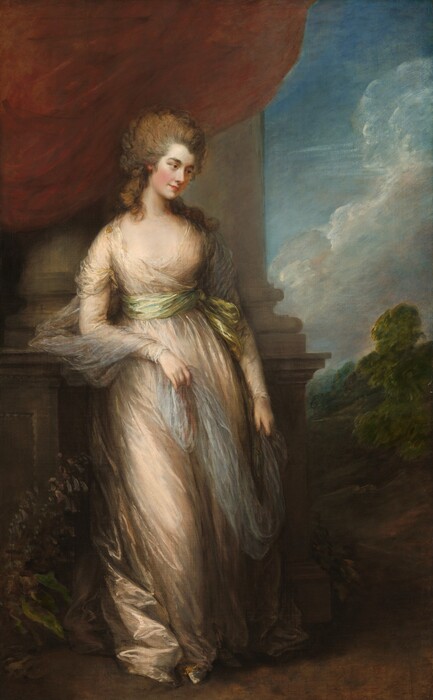 A woman with pale, smooth skin stands wearing a loosely draped, champagne-peach dress in this vertical portrait painting. Her body faces us but she turns her head to look down and off to our right with brown eyes. She has dark brows, an upturned nose, and her carnation-red lips are closed in a slight smile. Her ash-brown hair is loosely pulled up so it sweeps back from her face, while thick curls cascade down her neck and over her shoulders. Her long sleeved, floor-length dress is tied at her waist with a sage-green sash. Gossamer-white fabric drapes around her upper arms, and she holds the long ends in both hands. Her right elbow, to our left, rests on the high base of columns that rise behind her and off the top edge of the canvas. A rust-red curtain drapes down from the top of the painting, over the columns. To our right, beyond the columns, the landscape opens to a view of trees beneath a blue sky with white puffy clouds.