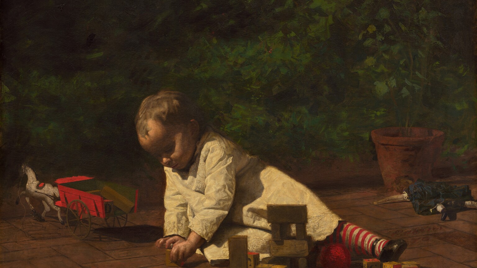 On the brick pavement of a sunny veranda, a young toddler leans heavily on her right arm, to our left, as she reaches for a wooden block in this horizontal painting. Much of her face is cast in deep shadow from the bright light overhead, but light brushes the tops of her cheeks and the tip of her nose. She grips a wooden block with her left hand, closer to us. Her left leg stretches to our right in a stocking striped with vivid red and white. Light glints off the shiny material of her black, round-toed slipper. She has short, golden-brown hair, and her white smock is richly embroidered in a pattern of white-one-white with alternating linked loops. Scattered before her, at arms-length, are seven other alphabet blocks lettered in gray with red and tan faces, several wooden building blocks, and a ball of red yarn. A doll in a black dress lies with limbs akimbo, face-down by a potted plant at the right edge of the canvas. A red wagon drawn by white toy horse sits near the left edge. The scene is enclosed with a deep, emerald-green hedge stretching across the background. The artist signed and dated this work as if he had inscribed two of the bricks on the patio with red paint in cursive script, in the lower right corner: “Eakins 76.”
