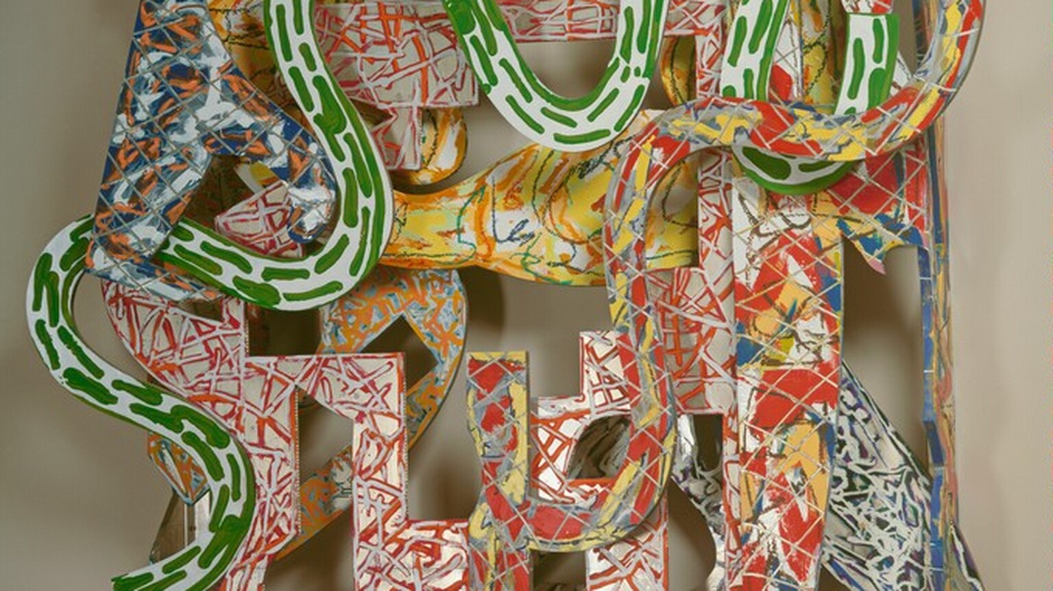Snake-like and geometric shapes covered with energetic patterns of vivid red, yellow, green, blue, and orange are layered to form this abstract, roughly oval sculpture, which hangs on a wall. The shapes have oval, rectangular, L-shaped, and square openings cut into them, and their patterns are created with scribbles, squiggles, dashes, and blobs of color like canary yellow, tomato red, lime green, cobalt blue, and white. The frontmost layer has undulating curves in kelly green on white. Other layers have red and yellow marks against gray, red and silver against white, and blue and silver. A tall rectangle on the right side extends slightly above and below the oval form of the rest of the sculpture.
