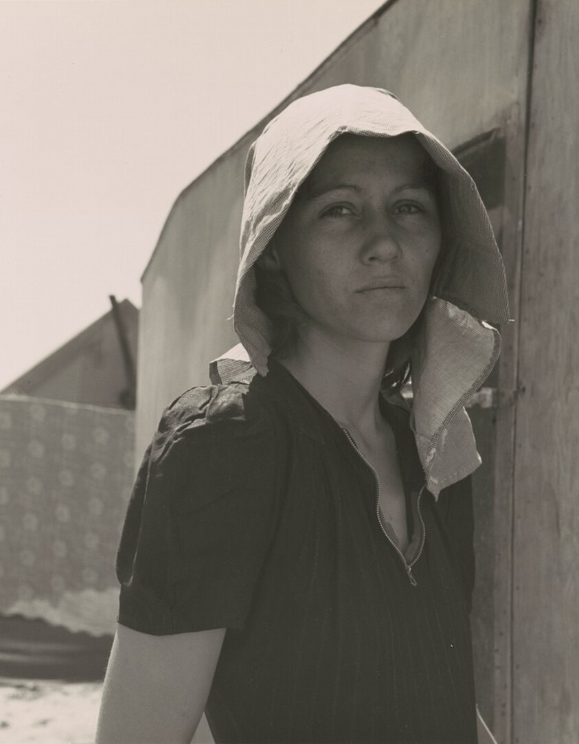 Young migratory mother, originally from Texas. On the day before the photograph was made, she and her husband traveled 35 miles each way to pick peas. They worked 5 hours each and together earned $2.25. They have two young children...Live in auto camp, Edison, Kern County, California